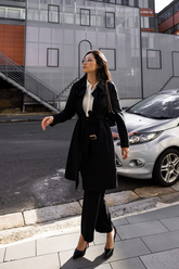 a lady in a white shirt, a black long coat and a pair of black pants